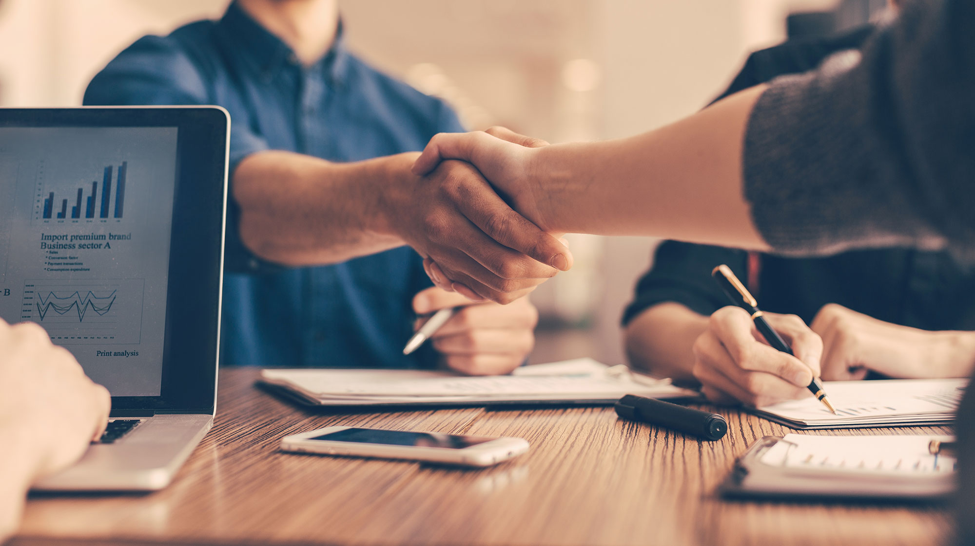 hand shake over table with laptop