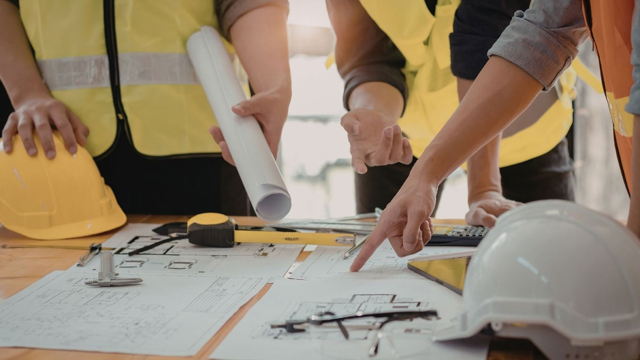 Construction team reviewing blue prints with hard hats
